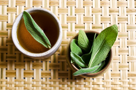Leaves of fresh sage on a background of ceramic cups with teaの写真素材