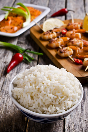 White rice cooked on a background of shrimp on skewers and salad with carrots. Selective focus.の写真素材