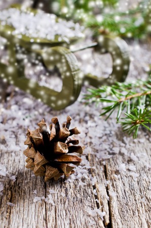 New Year composition with pine cones and sled on a wooden surface against a background of snowの写真素材