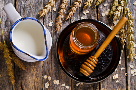 Liquid sweet honey on a background of milk and wheat ears. Selective focus.の写真素材