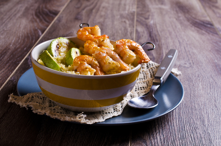 Fried shrimp on skewers with couscous and vegetables. Selective focus.の写真素材