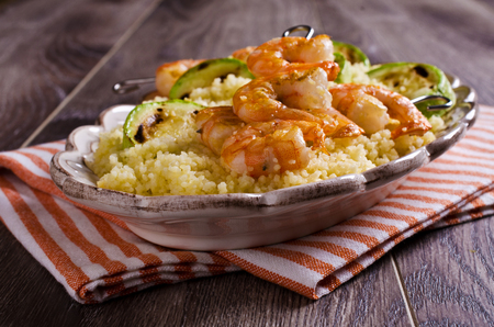 Fried shrimp on skewers with couscous and vegetables. Selective focus.の写真素材