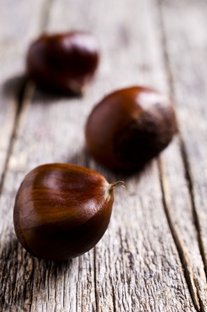 Ripe large chestnuts on a wooden surface. Selective focus.の写真素材