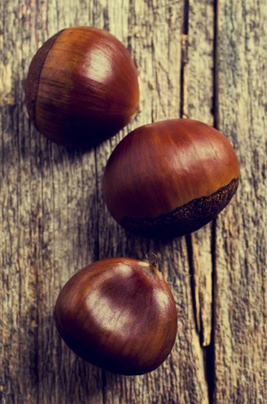 Ripe large chestnuts on a wooden surface. Selective focus.の写真素材