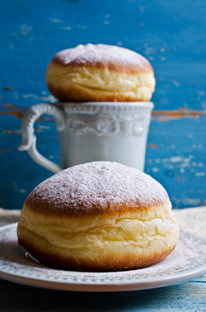 Donut in powdered sugar on a wooden background in rustic style. Selective focus.