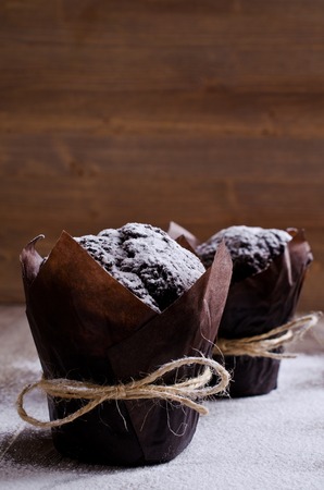 Chocolate muffin in baking paper on a wooden background. Selective focus.の写真素材
