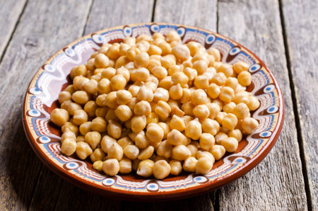 Grains of raw chickpeas in a pot on a wooden surface. Selective focus.の写真素材