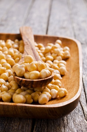 Grains of raw chickpeas in a wooden spoon. Selective focus.の写真素材