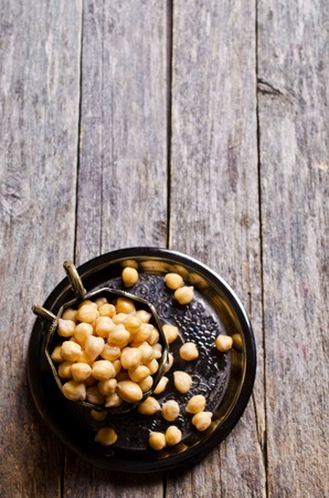 Grains of raw chickpeas in a pot on a wooden surface. Selective focus.の写真素材