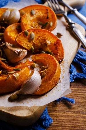 Slices of roasted pumpkin with garlic on a wooden background. Selective focus.の写真素材