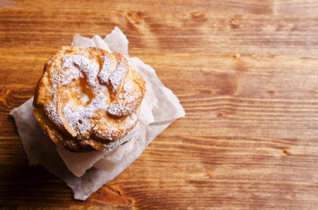Round cake with cream, sprinkle with powdered sugar,  on a wooden background. Selective focus.