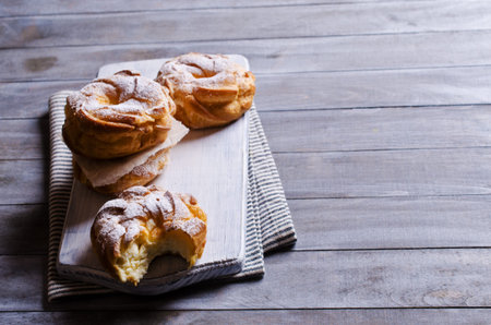 Round cake with cream, sprinkle with powdered sugar,  on a wooden background. Selective focus.