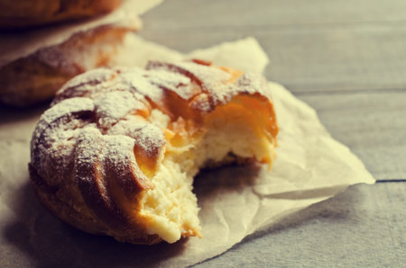 Round cake with cream, sprinkle with powdered sugar,  on a wooden background. Selective focus.