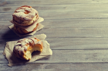 Round cake with cream, sprinkle with powdered sugar,  on a wooden background. Selective focus.の写真素材