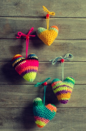 Knitted hearts of different colors on a wooden background. Selective focus.の写真素材
