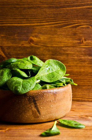 Leaves of fresh spinach in a bowl on a wooden background. Selective focus.の写真素材