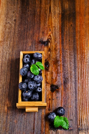 Fresh blueberries and mint in water drops on a wooden surface. Selective focus.の写真素材