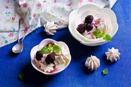 Dessert of meringue and cream with blackberries and mint. Selective focus.の写真素材