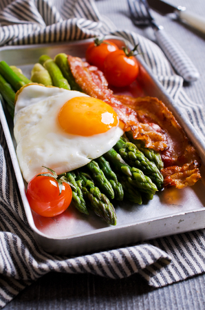 Green asparagus with fried eggs, bacon and tomatoes. Selective focus.の写真素材