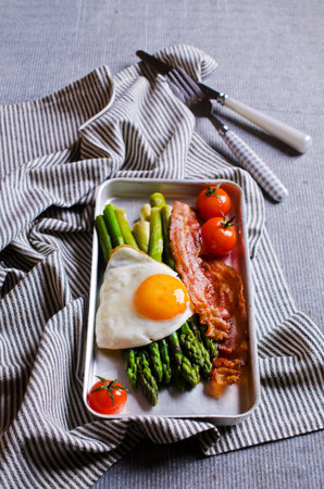Green asparagus with fried eggs, bacon and tomatoes. Selective focus.の写真素材