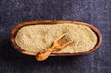 Quinoa dry seeds in a wooden bowl on a dark background. Selective focus.の写真素材