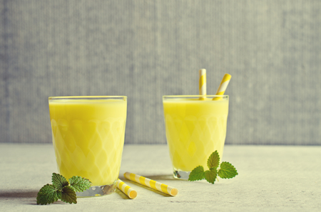 Yellow liquid in a glass on a light background. Selective focus.の写真素材