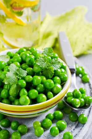 Green peas with mint in a bowl on a light background. Selective focus.の写真素材