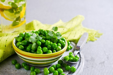 Green peas with mint in a bowl on a light background. Selective focus.の写真素材