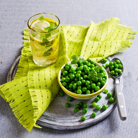 Green peas with mint in a bowl on a light background. Selective focus.の写真素材
