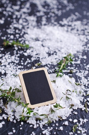 Board for an inscription with salt and thyme on a dark background. Selective focus.の写真素材