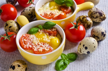 Fried of quail eggs with tomatoes and cheese in a batch manner. Selektivgy focus.の写真素材
