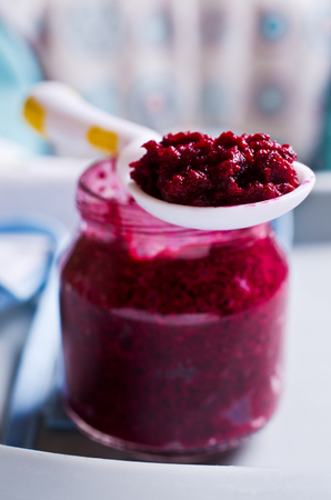 Baby food from beets on the table against the background of toys. Selective focus.の写真素材