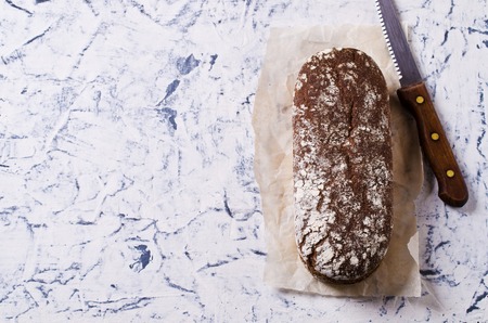 Loaf of rye bread on paper. Concrete background. Selective focus.の写真素材