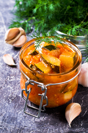Homemade canned zucchini with vegetables in red sauce. Selective focus.の写真素材