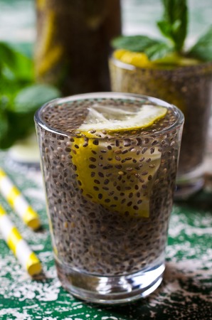 Transparent drink in a glass with chia seeds, lemon and mint on a wooden background. Selective focus.の写真素材