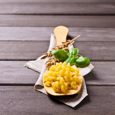 Dried pasta cavatappi in a spoon on a wooden background. Selective focus.の写真素材
