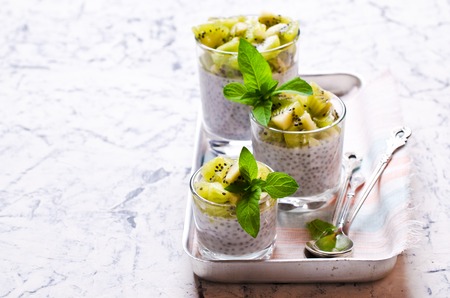 Dessert of cream, chia seeds and kiwi on a concrete background. Selective focus.の写真素材