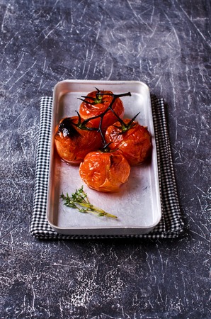 Baked tomatoes on a metal plate on a dark background. Selective focus.の写真素材