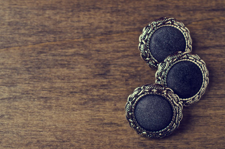 Round metal buttons in vintage style on a wooden background. Selective focus.の写真素材