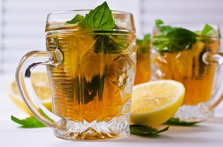 Cold tea with ice, lemon and mint on a wooden background. Selective focus.の写真素材