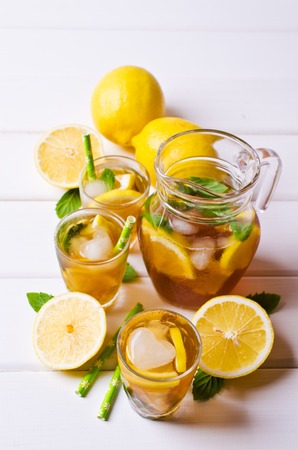 Cold tea with ice, lemon and mint on a wooden background. Selective focus.の写真素材