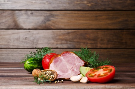 Piece of smoked meat with vegetables on a wooden background. Selective focus.の写真素材