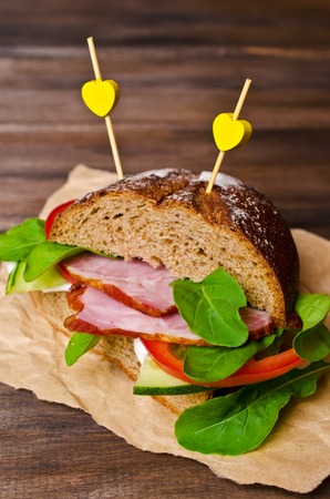 Sandwich with smoked meat and vegetables on a wooden background. Selective focus.の写真素材