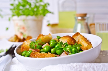 Salad with green peas, bacon and croutons on wooden background. Selective focus.の写真素材
