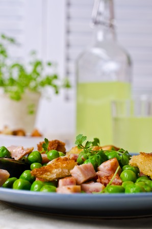 Salad with green peas, bacon and croutons on wooden background. Selective focus.の写真素材