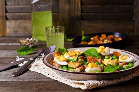 Salad with green peas, bacon and croutons on wooden background. Selective focus.の写真素材