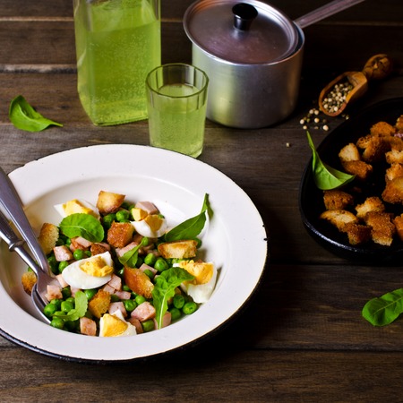 Salad with green peas, bacon and croutons on wooden background. Selective focus.の写真素材