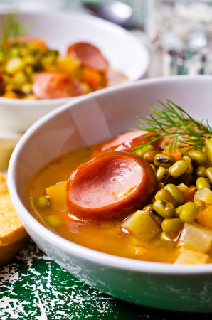 Homemade soup with beans, vegetables and sausages. Selective focus.の写真素材