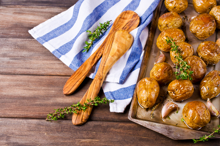 Young baked potatoes with garlic and thyme on a dark wooden background. Selective focus.の写真素材