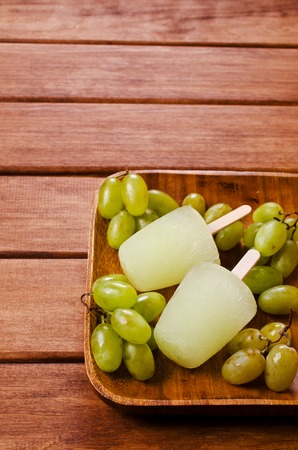 Ice lolly of green grapes on a wooden background. Selective focus.の写真素材